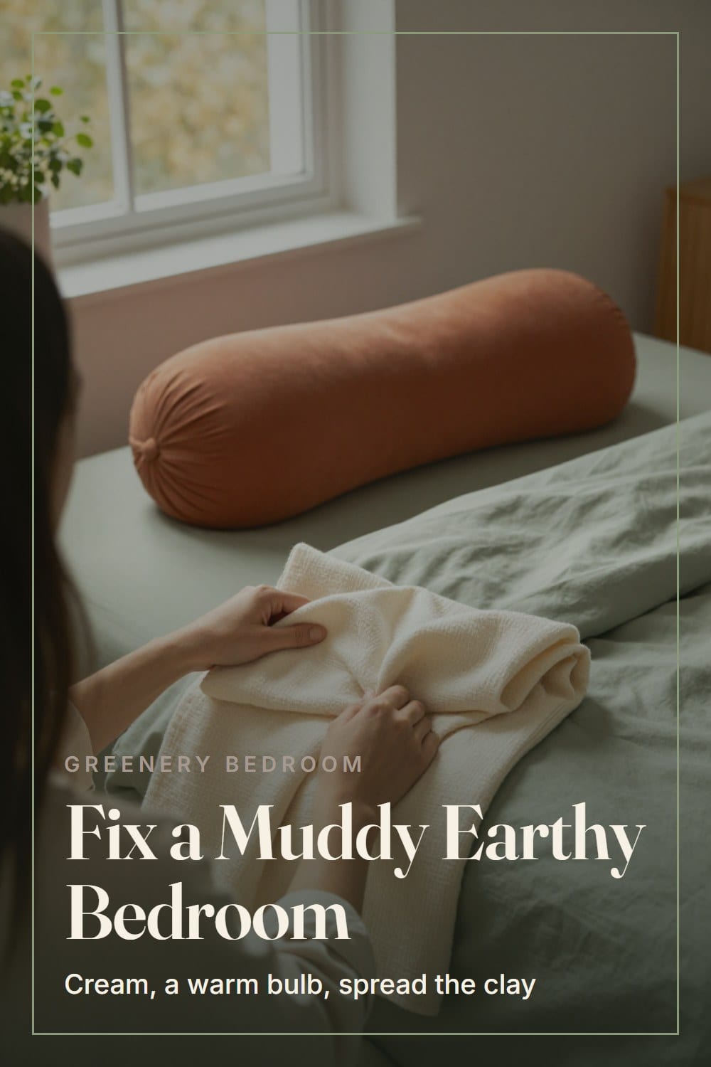 Over-the-shoulder view of a hand folding a cream linen throw onto a sage duvet beside a terracotta lumbar pillow