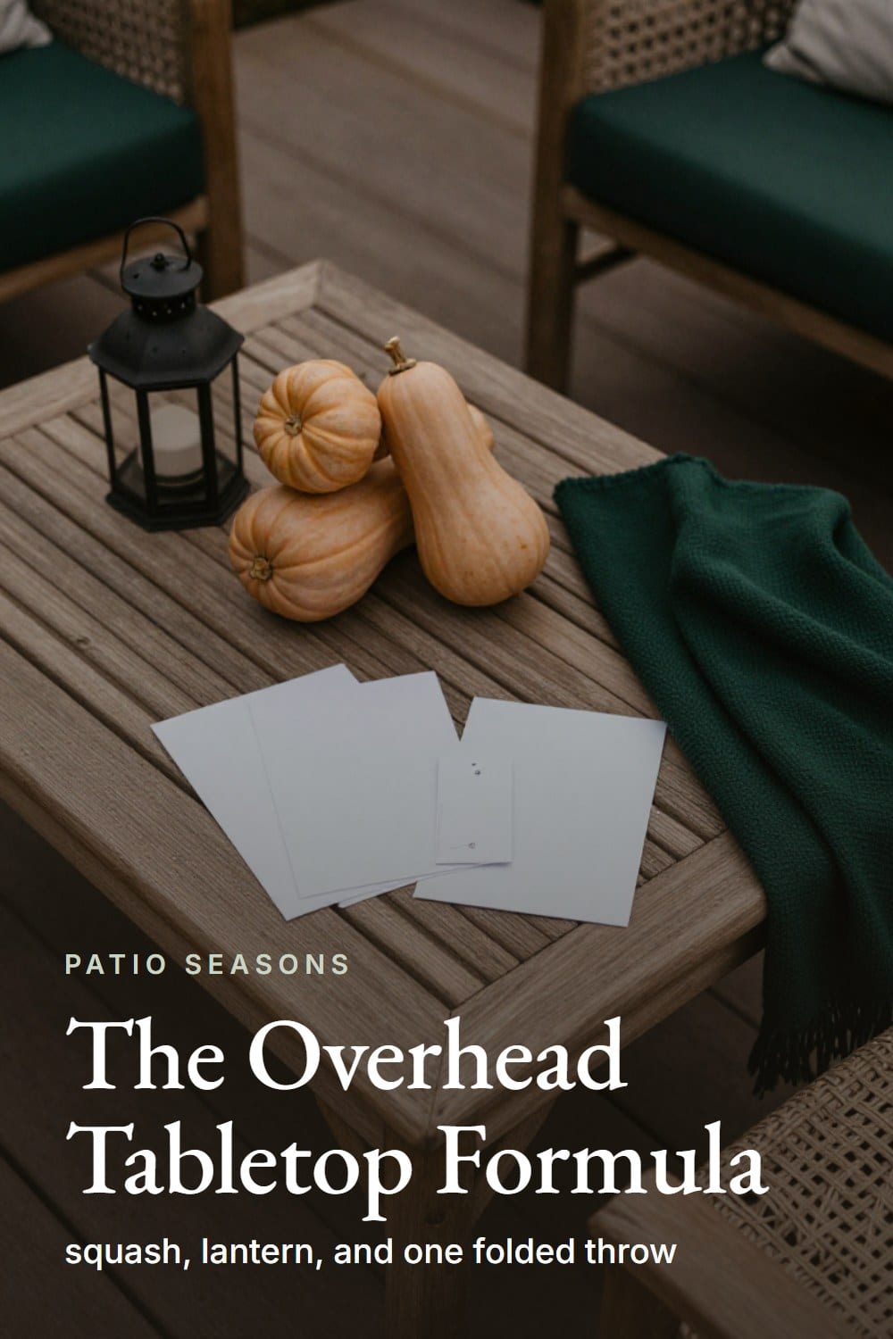 An overhead flat-lay of a fall patio coffee table styled with squash, a lantern, and a folded throw