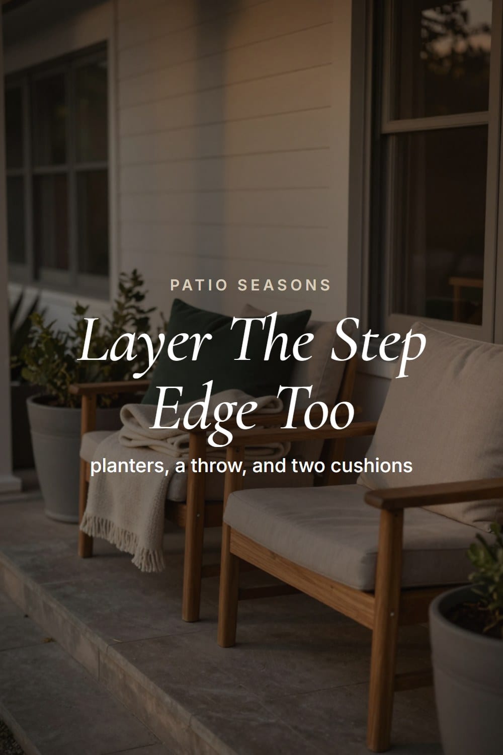 A grouping of fall planters along a porch step edge beside a bench dressed with cushions and a throw