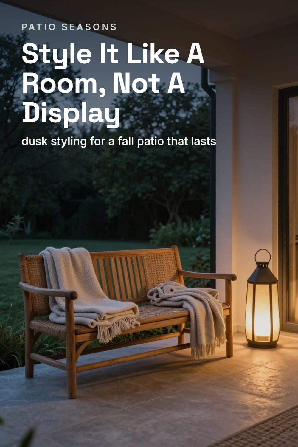 A wide dusk view of a fall patio styled as one finished outdoor room with teak furniture and layered throws