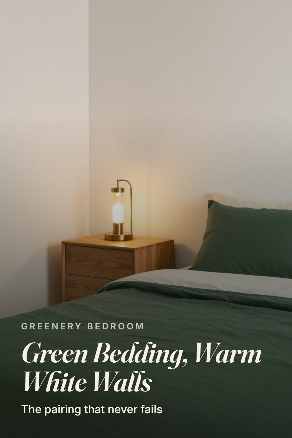 Forest green linen bedding on a made bed against warm white walls with a honey oak nightstand and glowing brass lamp