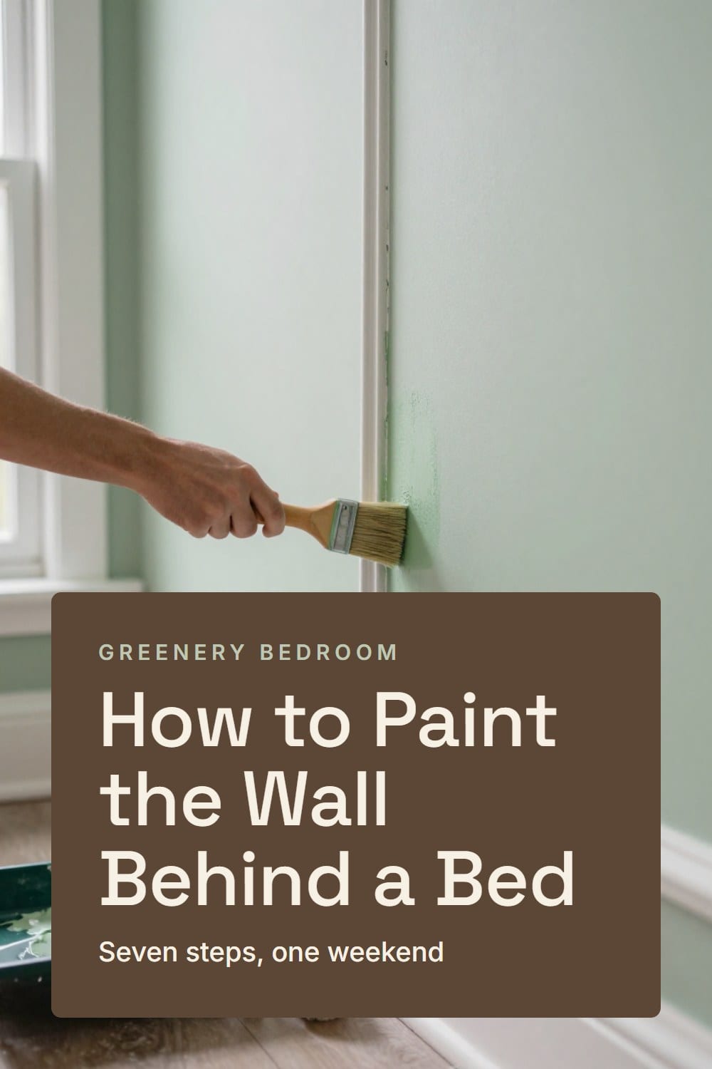 A hand brushing green paint along white-primed picture-frame molding on a bedroom wall