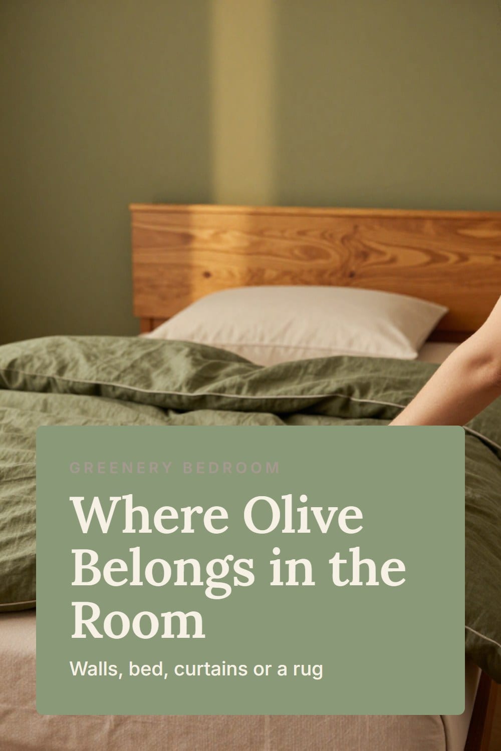 A hand smoothing an olive linen duvet beside a painted olive wall and a honey oak headboard on a real-home bed