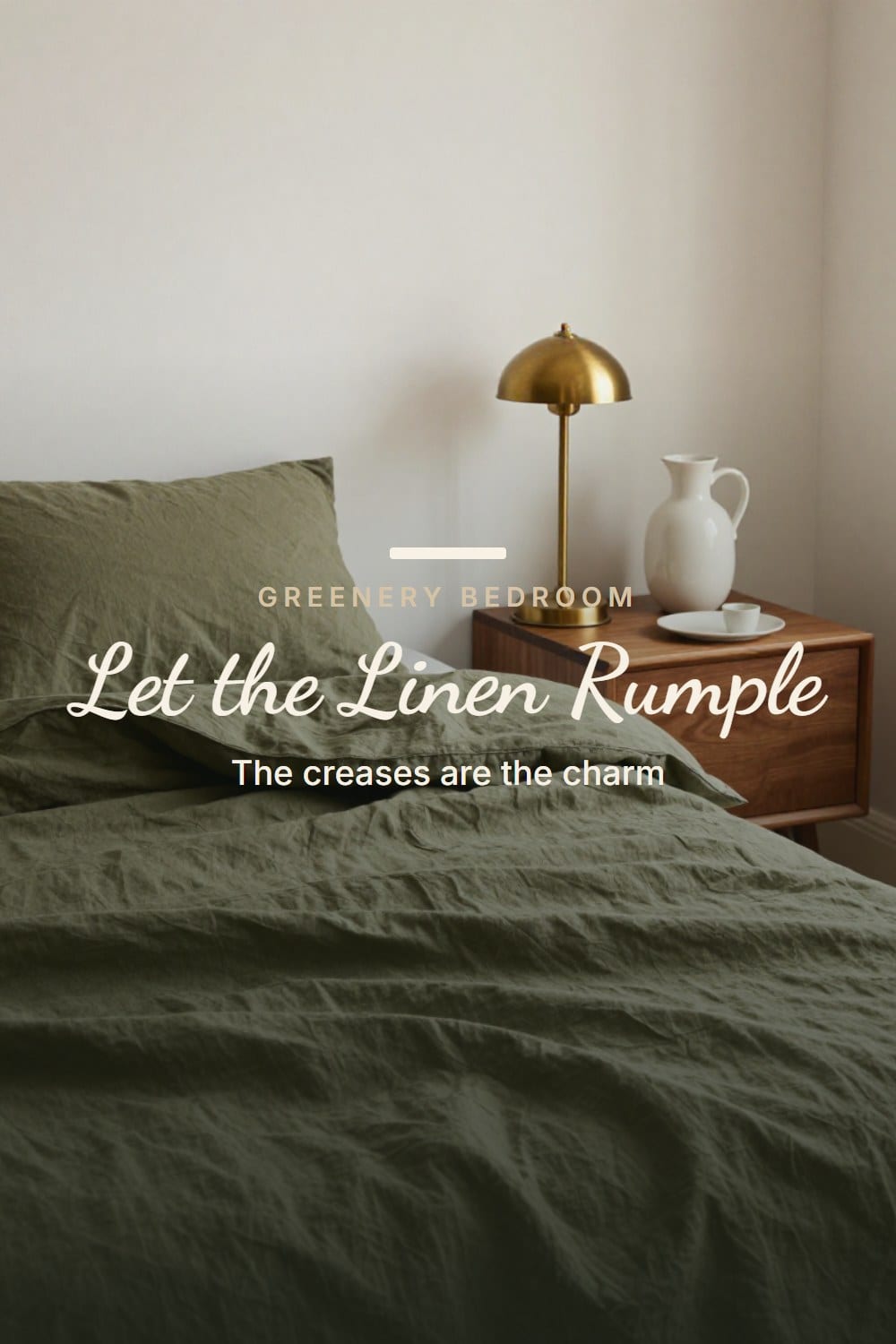 Rumpled washed olive linen bed in morning light with a brass lamp and ceramic carafe on a walnut nightstand
