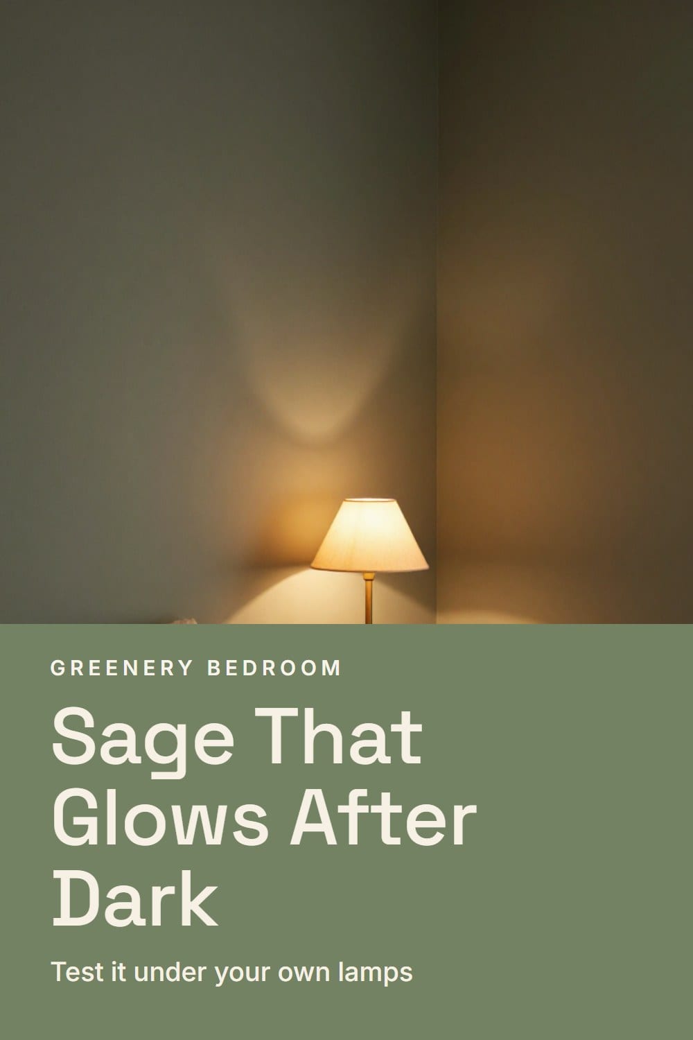 A bedroom with deep sage walls glowing softly around a bedside lamp, with rumpled linen bedding