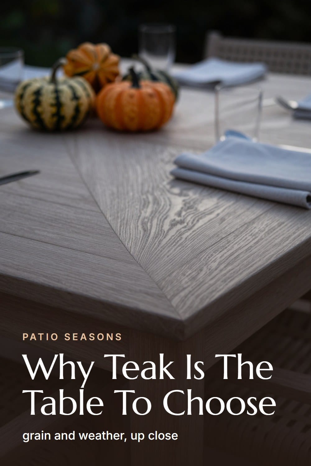 A macro close-up of silvered teak grain at the corner of a dining table beside a folded linen napkin
